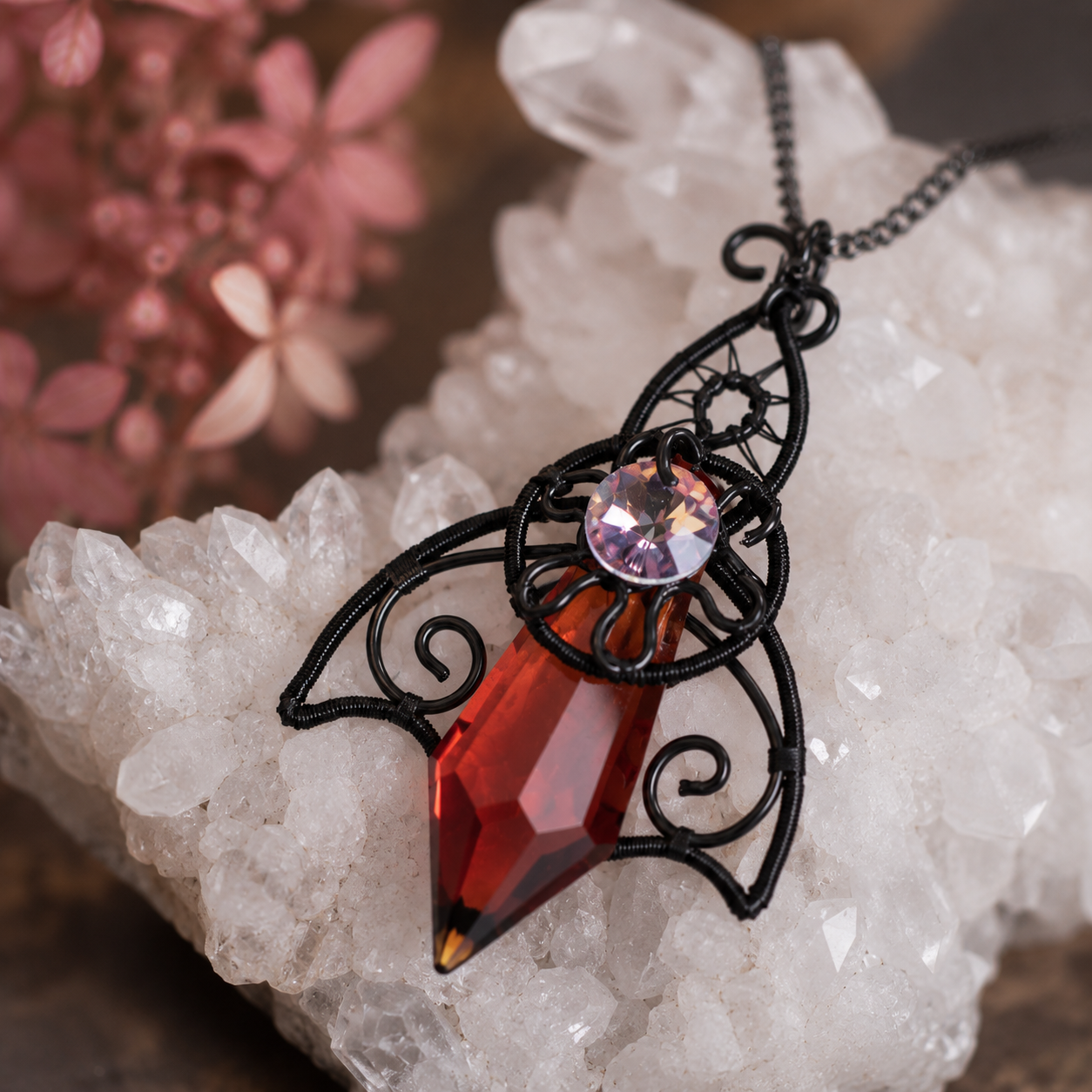 Close-up of handcrafted Twilight Talisman pendant showing black enamelled copper wire and faceted red glass crystal